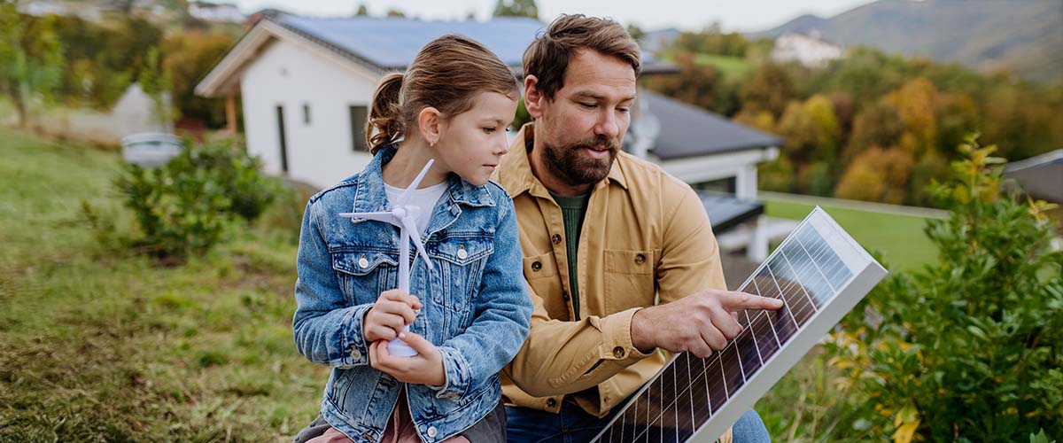 Vater zeigt seiner Tochter ein Solarmodul – Symbolbild für nachhaltige Energie, Photovoltaik und Investition in die Zukunft.