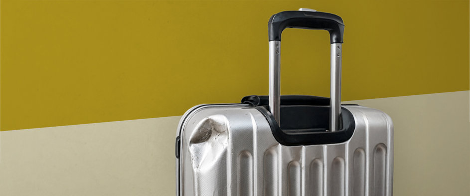 Beschädigter Hartschalenkoffer mit eingedrückter Ecke – Symbolbild für Reiserisiken und den Schutz vor finanziellen Folgen durch eine Reiseversicherung.